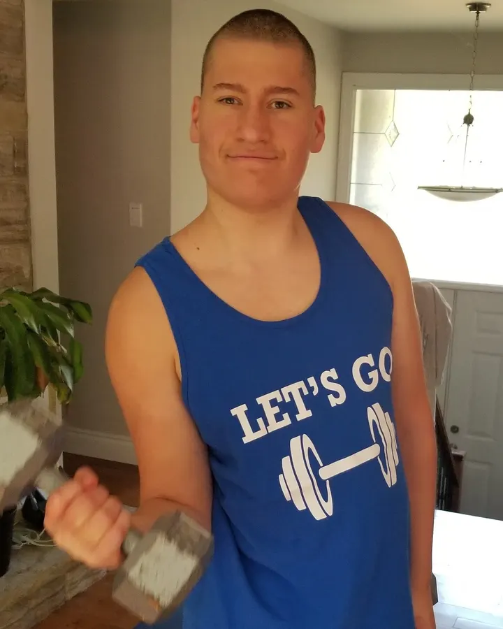 Dante, a Let's Go Fitness trainer, smiling and curling a dumbbell at home